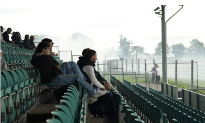 Soccer fans watching a live match on a phone in a stadium stand