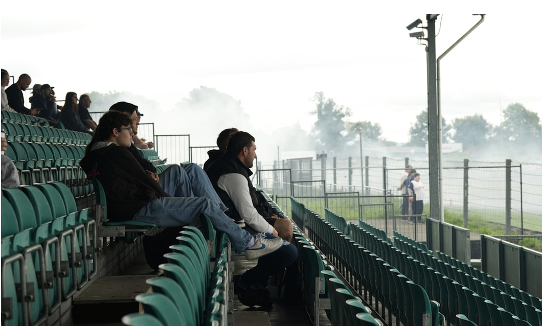 Soccer fans watching a live match on a phone in a stadium stand