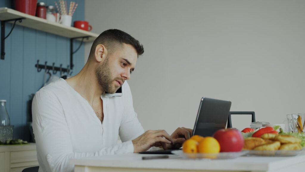 Alt text: An adult reading about how a casino app works on a laptop at a kitchen table
